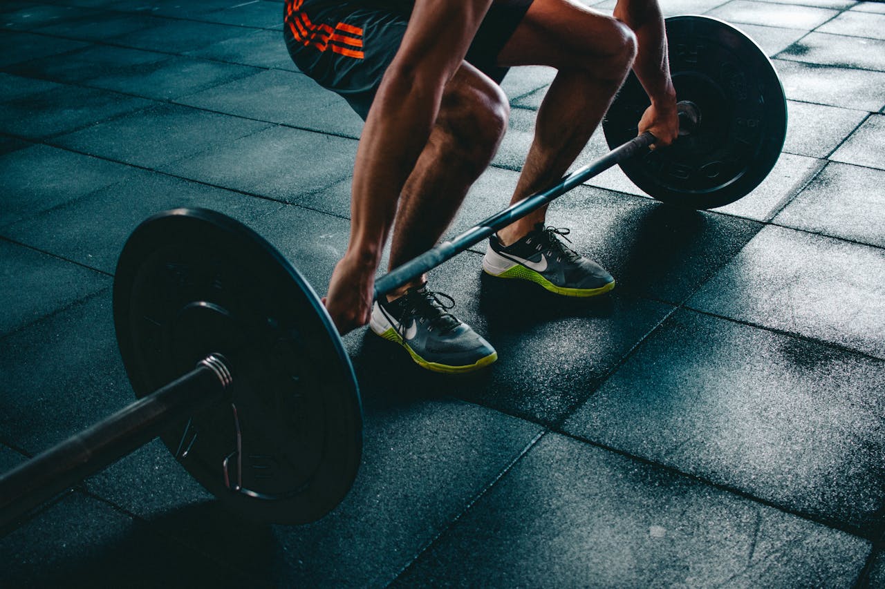Gros plan sur les jambes d’un homme soulevant une barre de musculation au sol